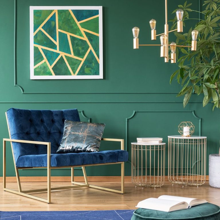 Amenajare living stil minimalist - perete verde, corp iluminat cu 6 becuri, tablou, fotoliu cu sezut albastru din catifea, carte deschisa, 2 masute decorative